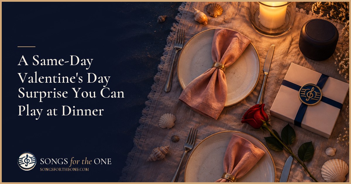 A couple at a candlelit dinner, listening to a song from a small speaker beside a phone and a handwritten card.