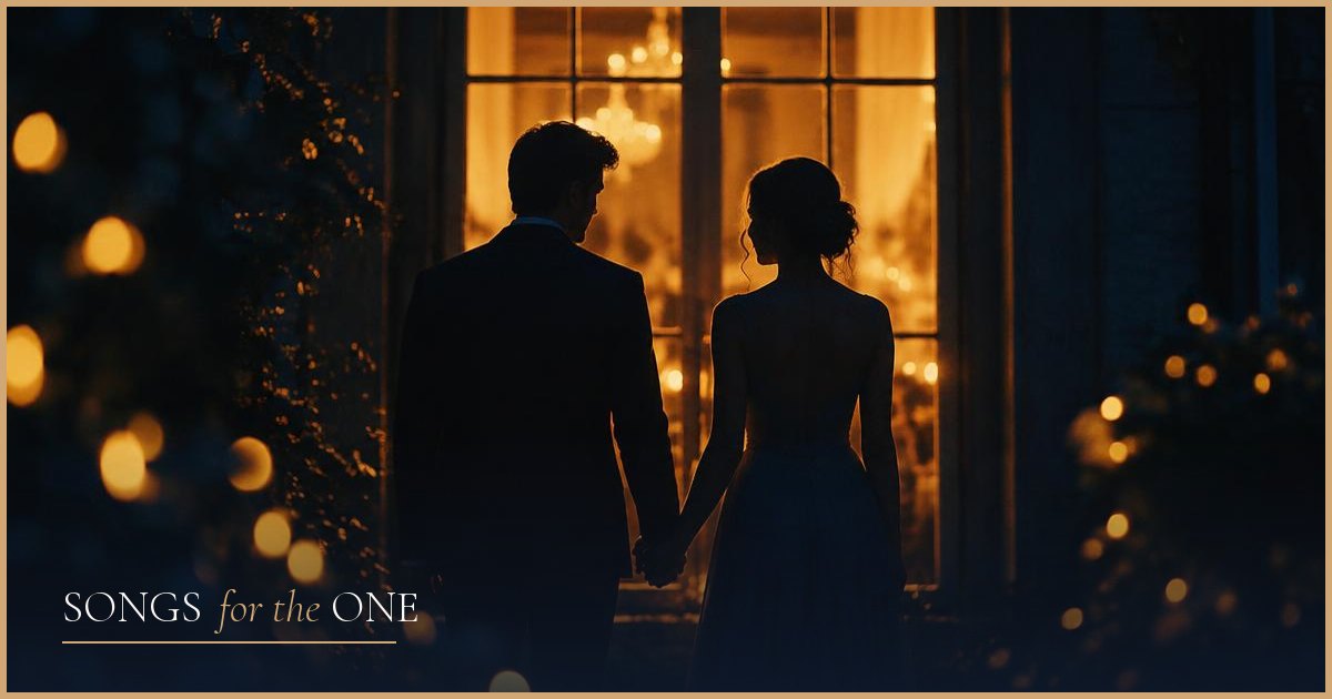 A couple holding hands in front of a warmly lit window at night