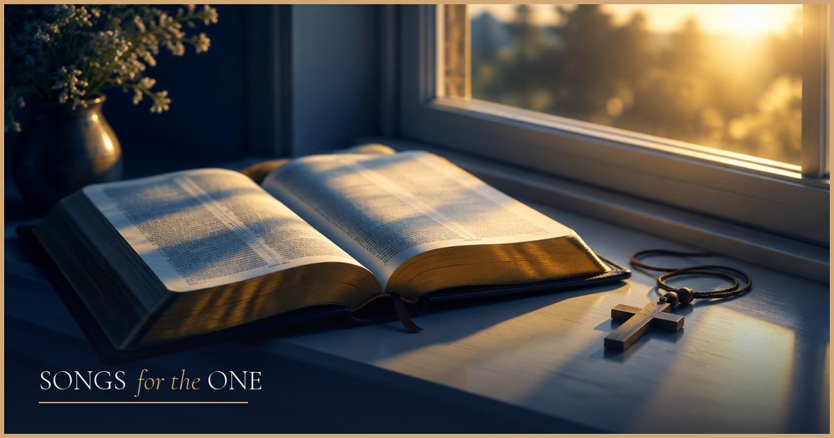 An open Bible and a wooden cross necklace on a sunlit windowsill